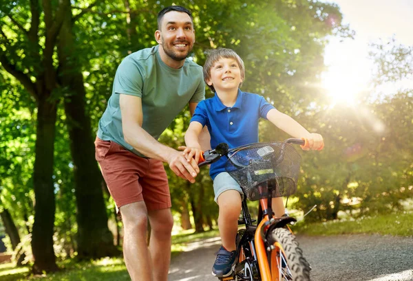 Otec učí malého syna jezdit na kole v parku — Stock fotografie