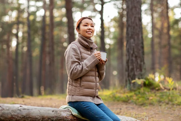 Asian woman with mug drinking tea in forest — Stock Photo, Image
