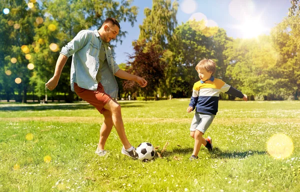 Pai com pequeno filho jogando futebol no parque — Fotografia de Stock