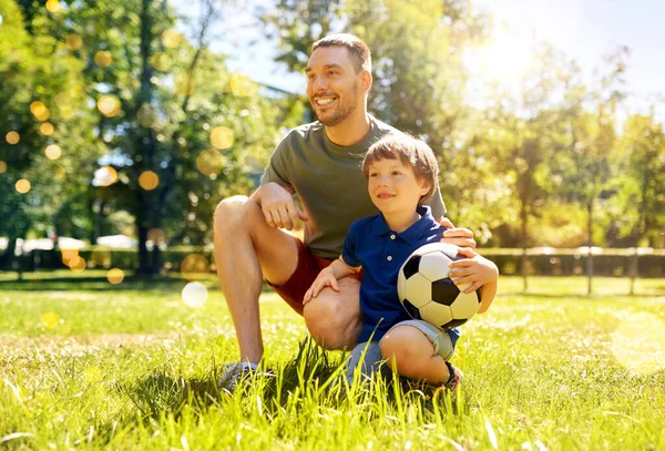 Pai e filho pequeno com bola de futebol no parque — Fotografia de Stock