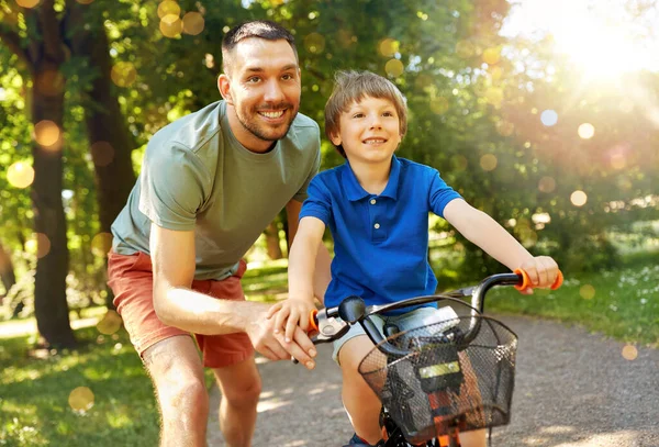 Padre enseñando a su hijo a montar en bicicleta en el parque — Foto de Stock