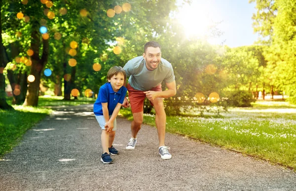 Счастливый отец и сын соревнуются в беге в парке — стоковое фото