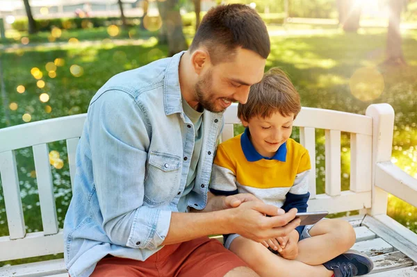 Otec a syn s chytrým telefonem v parku — Stock fotografie