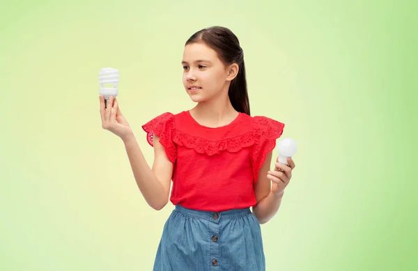 Chica sonriente comparando diferentes bombillas — Foto de Stock