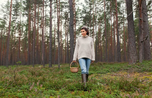 Vrouw met mand plukken paddestoelen in bos — Stockfoto