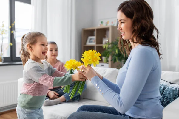 Filhas dando flores de narciso para mãe feliz — Fotografia de Stock