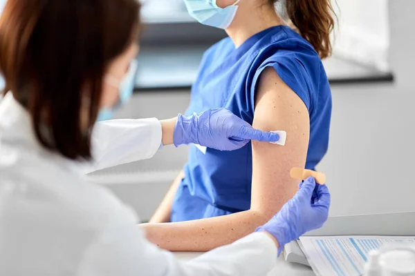 Doctor adjuntando parche al trabajador médico —  Fotos de Stock