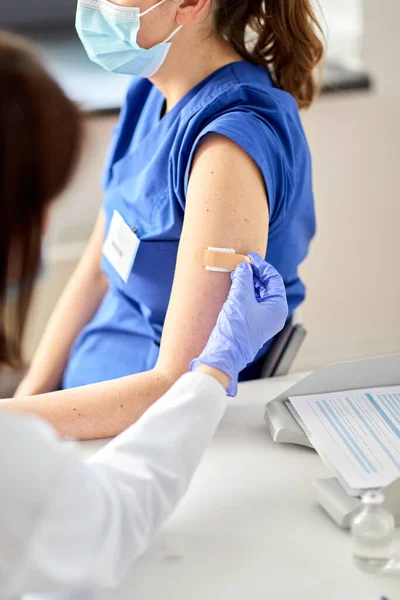 Doctor adjuntando parche al trabajador médico —  Fotos de Stock