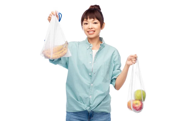 Vrouw met fruit in herbruikbare en plastic zakken — Stockfoto