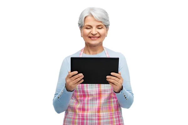 Усміхнена старша жінка в фартусі з планшетним комп'ютером — стокове фото