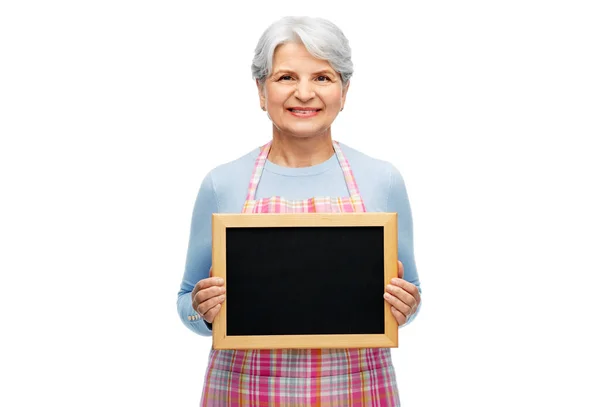 Lächelnde Seniorin in Schürze mit Kreidetafel — Stockfoto