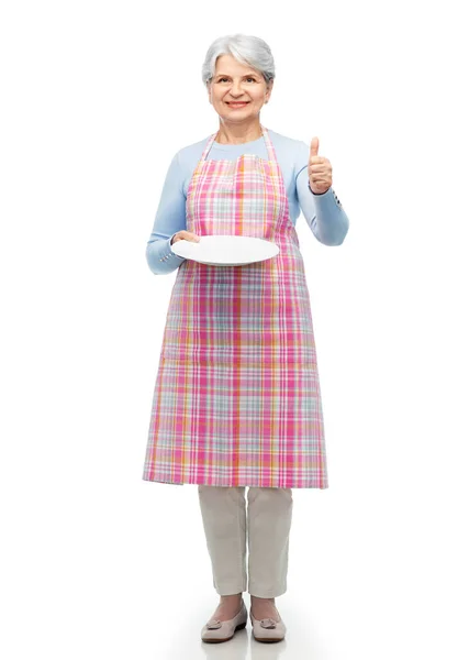 Old woman in apron with plate showing thumbs up — Stock Photo, Image