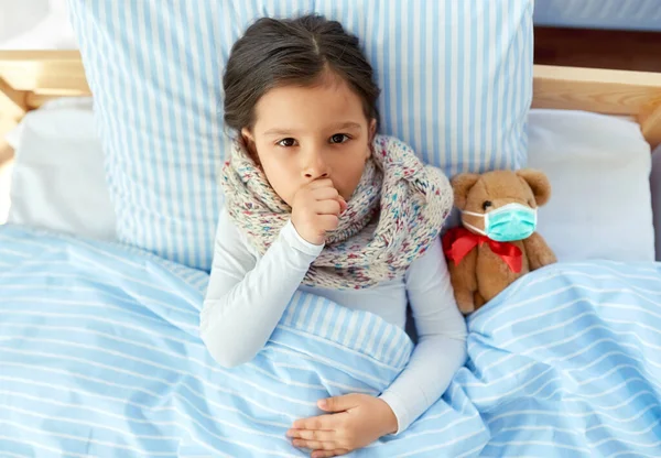 Doente tosse menina com ursinho de pelúcia deitado na cama — Fotografia de Stock