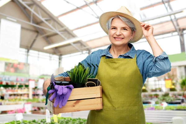 Senioren vrouw met gereedschap in doos in tuin winkel — Stockfoto
