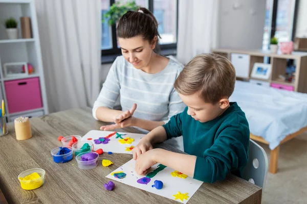 Mãe e filho brincando com argila modelagem em casa — Fotografia de Stock