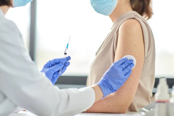 Vrouwelijke arts met injectiespuit vaccinerende patiënt — Stockfoto