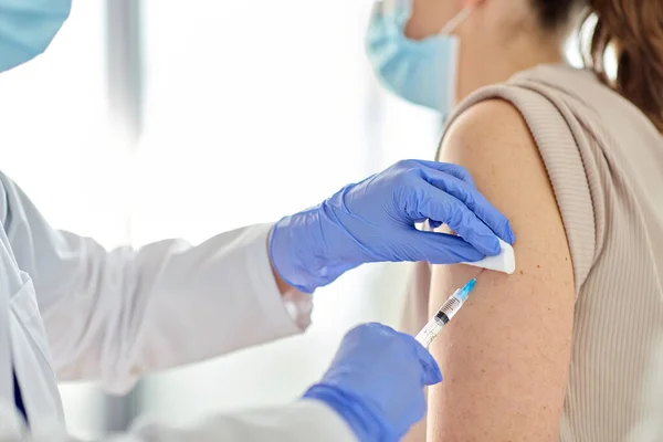 Vrouwelijke arts met injectiespuit vaccinerende patiënt — Stockfoto