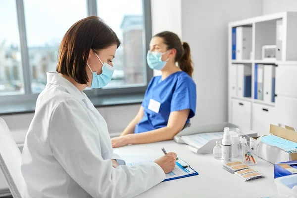 Doctor with clipboard and nurse at hospital — Stock Photo, Image