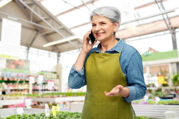 Seniorin telefoniert mit Smartphone im Gartengeschäft — Stockfoto