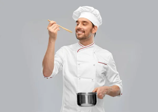 Happy smiling male chef with saucepan tasting food — Stock Photo, Image