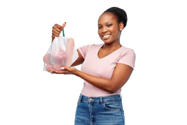 Mujer feliz con verduras en bolsa de red reutilizable — Foto de Stock