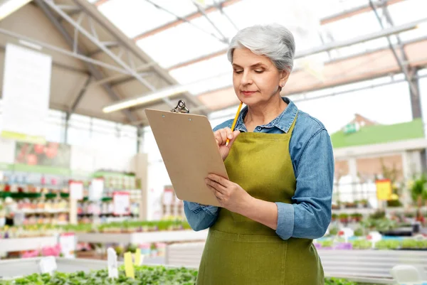 Senior kvinna med urklipp i trädgårdsbutiken — Stockfoto