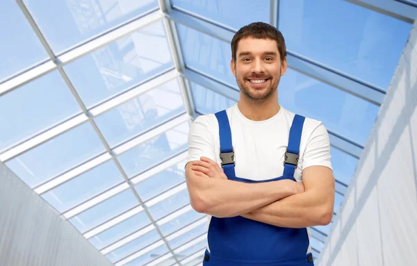 Szczęśliwy uśmiechnięty mężczyzna pracownik lub budowniczy w szklarni — Zdjęcie stockowe