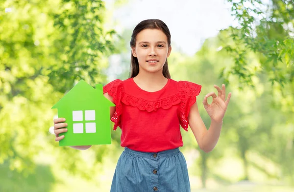 Niña feliz con icono de casa verde mostrando ok — Foto de Stock