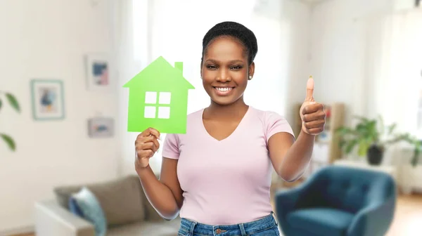 Усміхнена афроамериканська жінка тримає зелений будинок — стокове фото