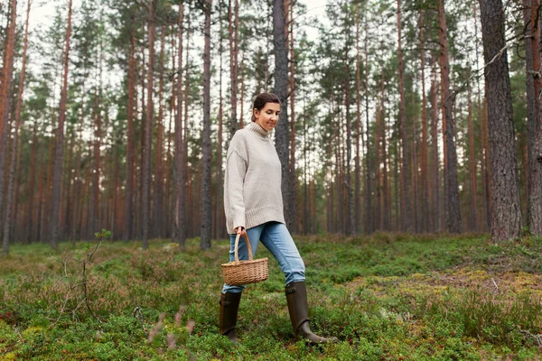 Vrouw met mand plukken paddestoelen in bos — Stockfoto