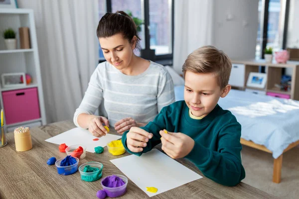 Moeder en zoon spelen met modelleren klei thuis — Stockfoto