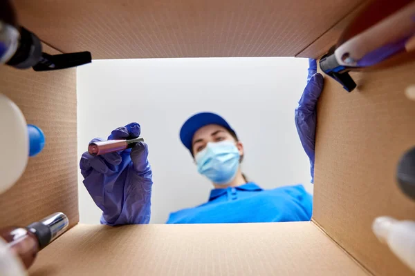 Kvinna i mask förpackning paket låda med kosmetika — Stockfoto