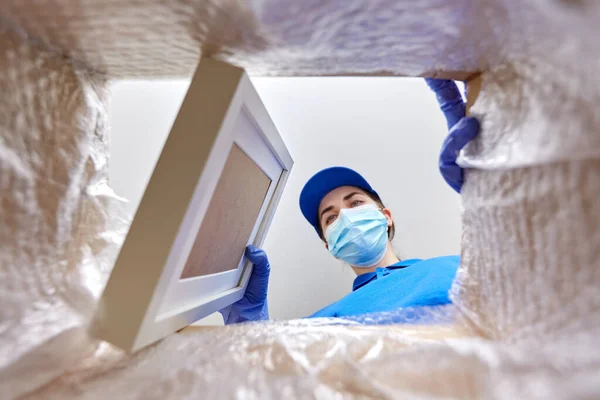 Woman in mask packing photo frame to parcel box — Stock Photo, Image