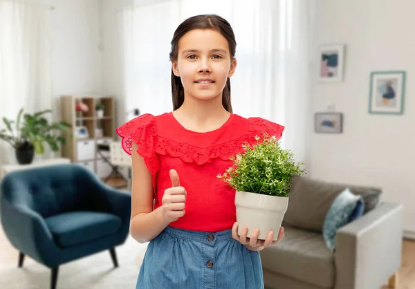 Gelukkig meisje holding bloem in pot tonen duimen omhoog — Stockfoto