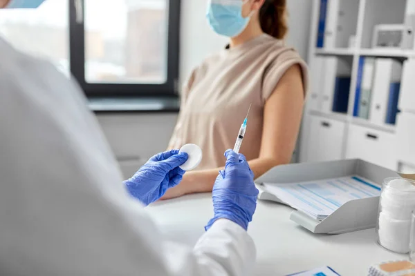 Vrouwelijke arts met injectiespuit vaccinerende patiënt — Stockfoto