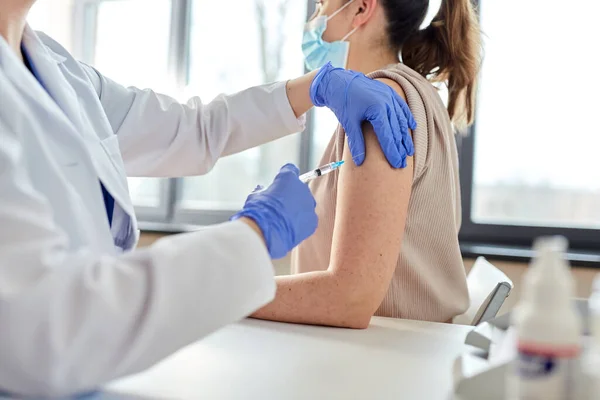 Vrouwelijke arts met injectiespuit vaccinerende patiënt — Stockfoto