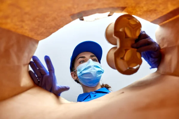 Levering meisje in handschoenen en masker met voedsel in zak — Stockfoto