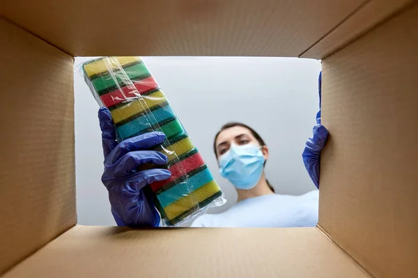 Vrouw in masker het nemen van schoonmaakmiddelen uit doos — Stockfoto