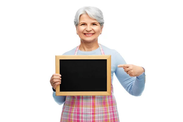 Lächelnde Seniorin in Schürze mit Kreidetafel — Stockfoto