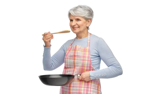 Leende äldre kvinna i förkläde med stekpanna — Stockfoto