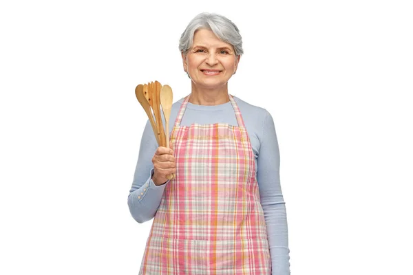 Mulher sênior sorridente em avental com colheres de madeira — Fotografia de Stock