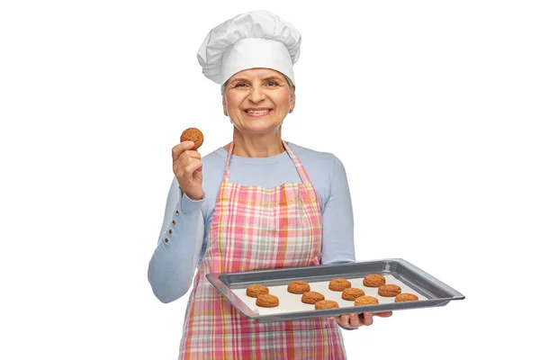 Пожилая женщина в токе с печеньем на сковороде — стоковое фото