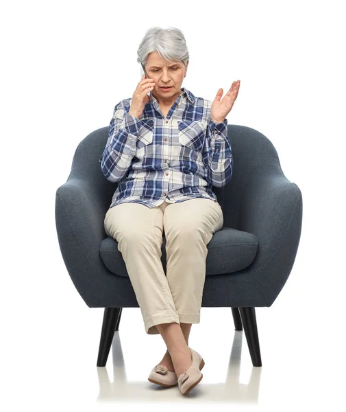 Senior woman calling on smartphone in armchair — Stock Photo, Image