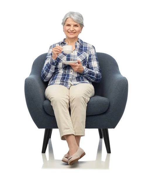 Mosolygó idős nő iszik kávét karosszékben — Stock Fotó