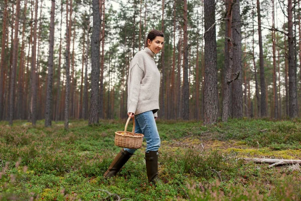 Mujer con cesta recogiendo setas en el bosque — Foto de Stock