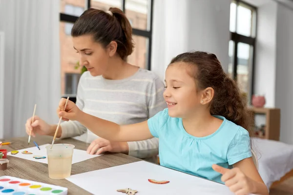 Счастливая мать с маленькой дочкой рисует дома — стоковое фото