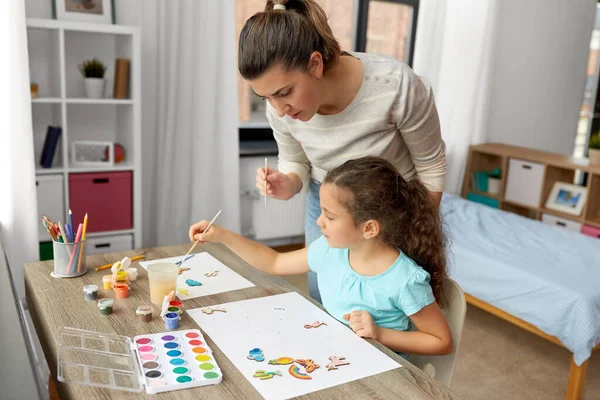 Мати з маленькою дочкою малює вдома — стокове фото