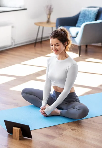 Mujer joven con tablet pc haciendo yoga en casa — Foto de Stock