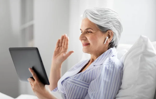 Mulher velha com tablet pc ter chamada de vídeo na cama — Fotografia de Stock