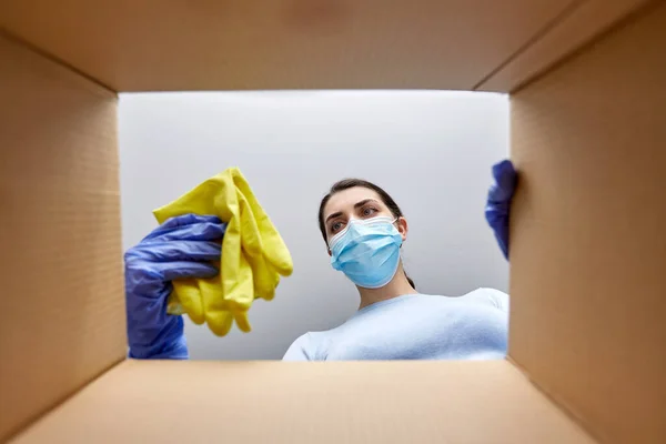 Vrouw in masker het nemen van schoonmaakmiddelen uit doos — Stockfoto
